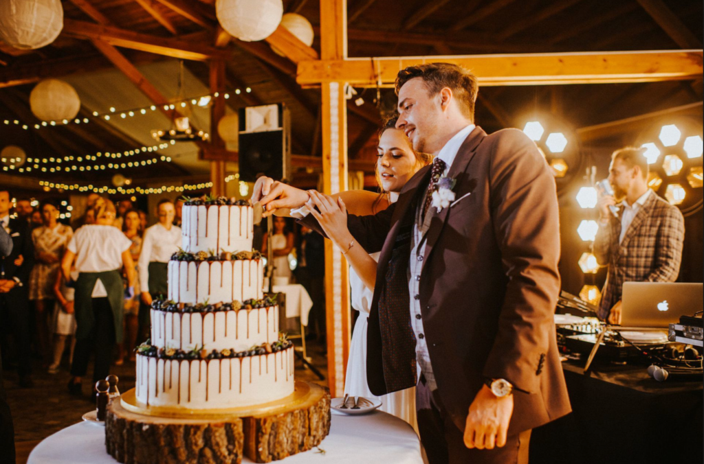 Para Młoda kroi tort na weselu w stylu boho/rustykalnym